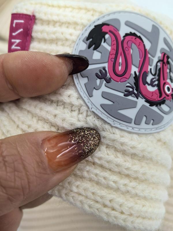 Kremfarget strikket vinterbeanie med rosa slange-merke og glitterdetalj