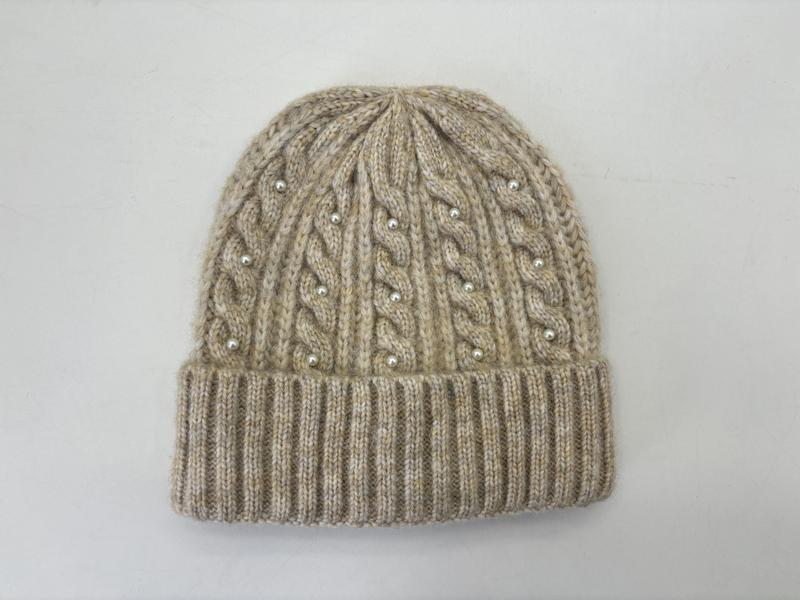 Beige strikket lue med perledetaljer og ribbet kant.
