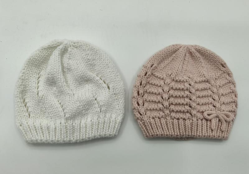 To håndstrikkede babyluer i hvit med løvmønster og rosa med horisontale riller og sløyfe.