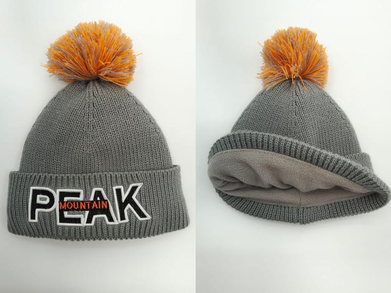 Grå strikket vinterlue med oransje pom-pom