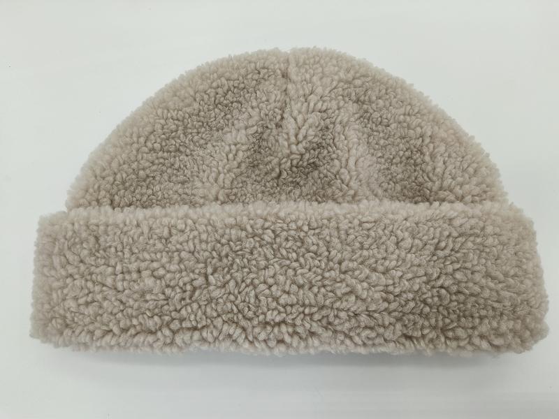 Beige kyseformet lue i krøllet sherpa-fleece med oppbrettede mansjetter