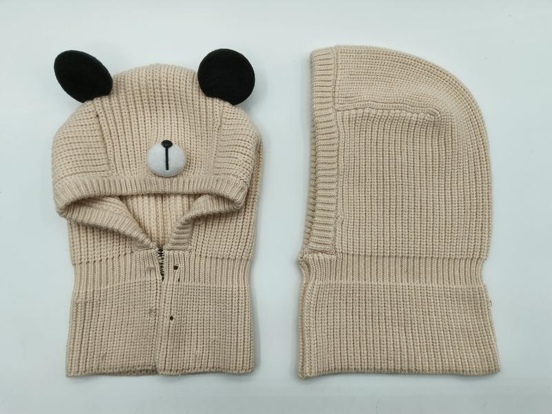 Beige grovstrikket bjørnebalaklava med svarte ører og brodert ansikt.