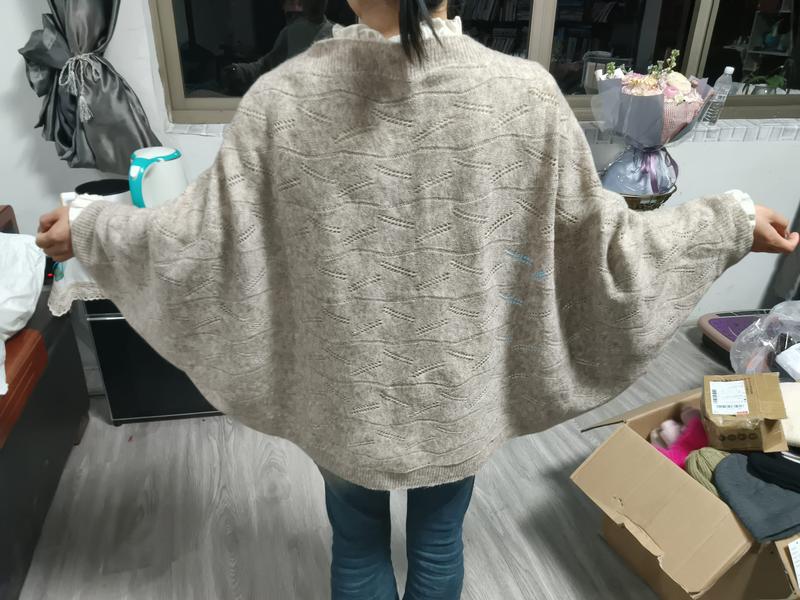 Beige oversized strikket genser med flaggermusermer og dekorativt hullmønster.