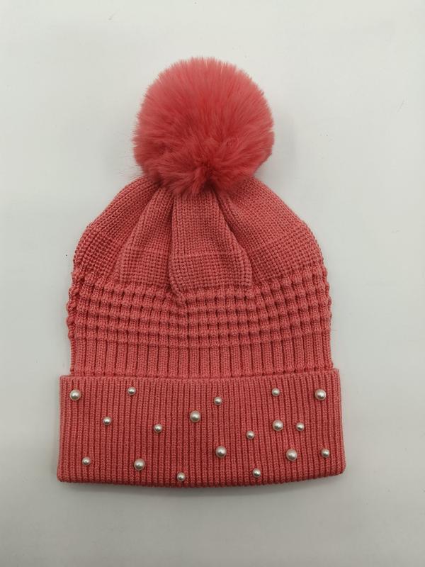 Korallrosa strikket lue med perledekorasjoner og pompom på toppen.
