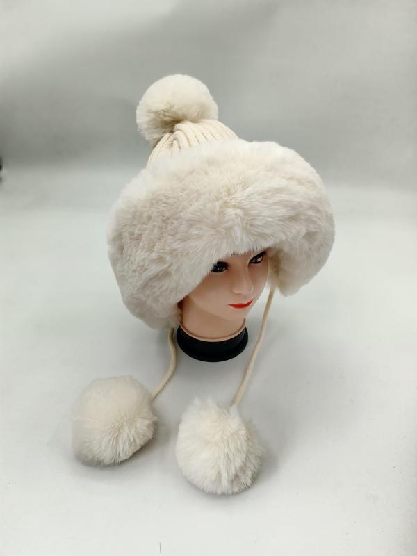 Kremhvit kunstpels trapper-lue med strikket pompom på toppen og dinglende pelsbånd til binding.