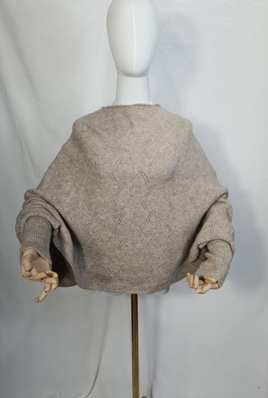 Bakside av oversized pointelle-strikket genser i havregryn-beige med ballongärmer på hvit mannequin.