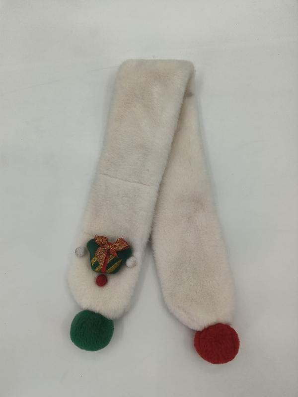Kremfarget kunstpelsskjerf med røde og grønne pompomer og brodert julebjellenål på hvit bakgrunn.