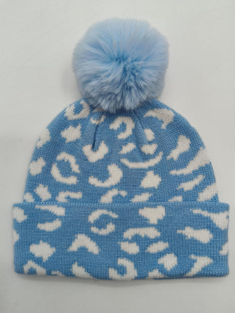 Lyseblå og hvit leopardmønstret strikket vinterlue med fluffy kunstpels-pompom på toppen.