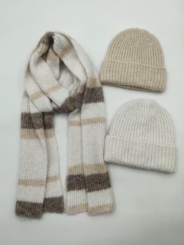Beige og kremhvit ribbestrikket lue med matchende stripet skjerf i nøytrale farger på hvit bakgrunn.