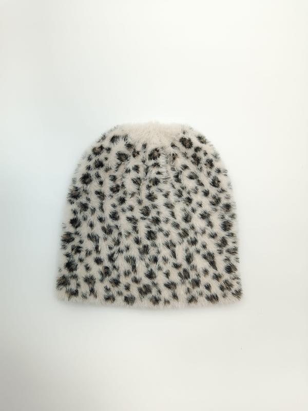 «Flat lay av fluffy kremfarget lue med sort og brun leopardmønster på hvit bakgrunn»