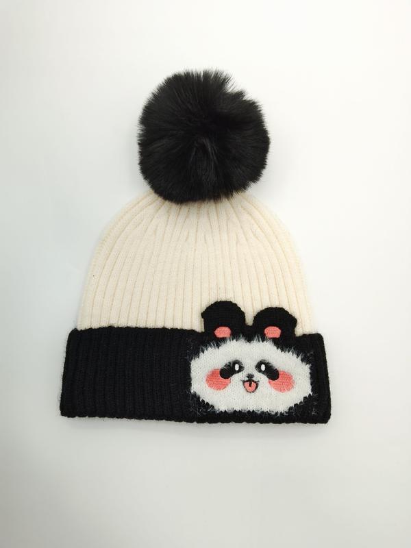 «Svart og kremfarget ribbestrikket lue med pandamotiv og stor svart kunstpels-pompom»