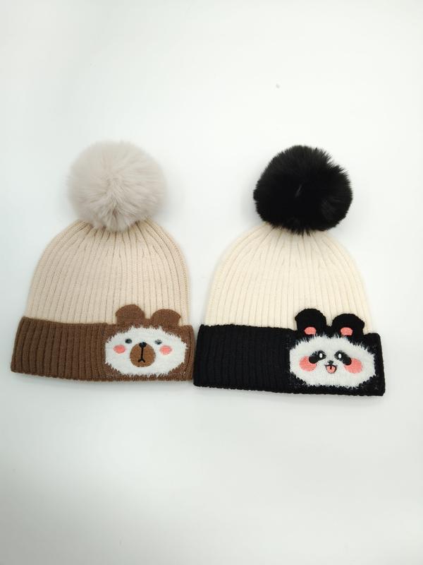 To strikkeluer med pompom: bjørndesign på beige lue og pandadesign på sort/kremfarget lue.