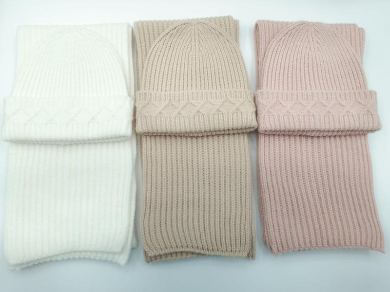 Tre matchende sett med grovstrikket lue og ribbestrikket skjerf i elfenbein, taupe og blush rosa på hvit bakgrunn.