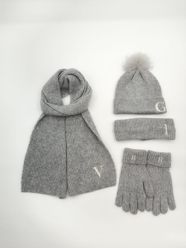 Grå ribbstrikket vinterset med pompomhue, skjerf, pannebånd og votter med monogram.