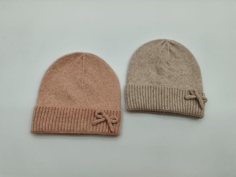 To myke strikkeluer med sløyfe i rosa og beige, flatlagt med ribbekant.